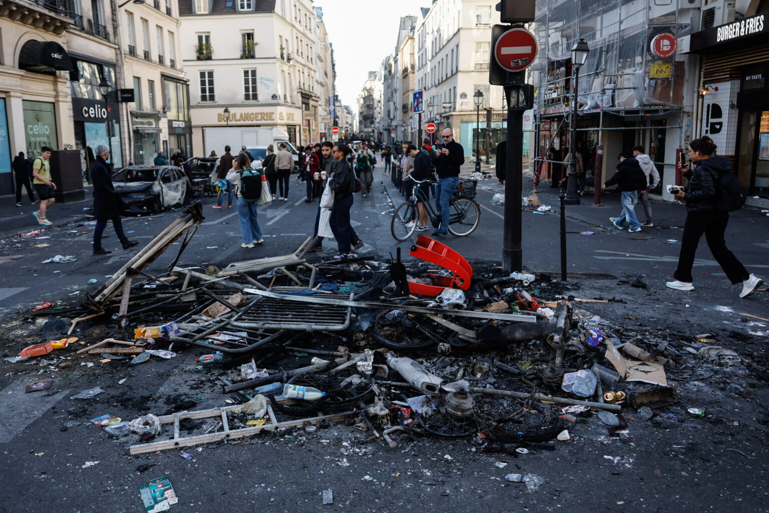 Gobierno francés admite fallos policiales tras disturbios y saqueos en varias ciudades Unas personas pasan junto a los restos de una hoguera callejera tras los enfrentamientos entre la policía antidisturbios y los manifestantes en París
